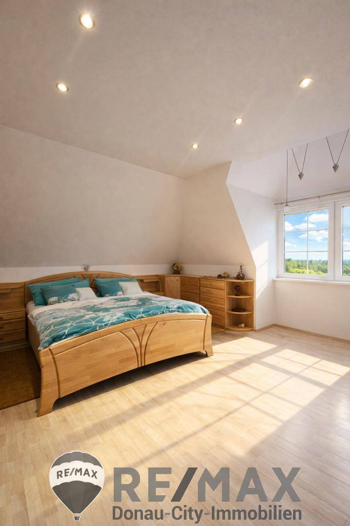 Helles Schlafzimmer mit Holzdoppelbett, Kommoden und Parkettboden, sonnendurchflutet.