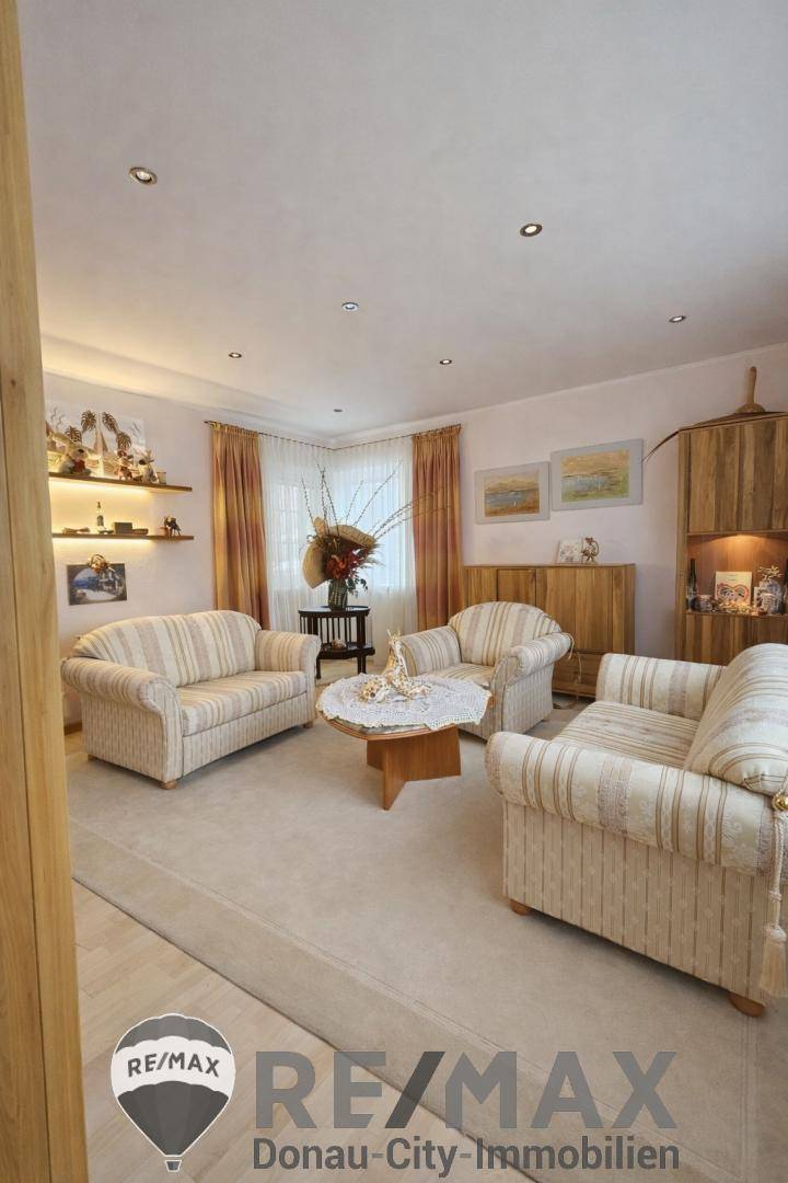 Gemütliches Wohnzimmer mit gestreiften Sofas, Teppichboden und indirekter Beleuchtung.