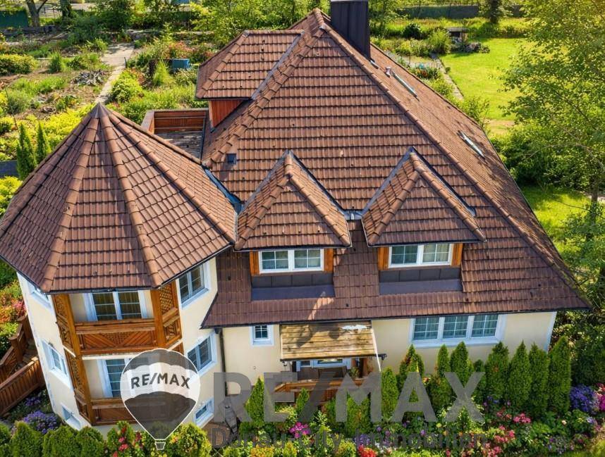 Dachansicht des Hauses mit mehreren Giebeln und braunen Ziegeln, umgeben von gepflegter Gartenanlage.