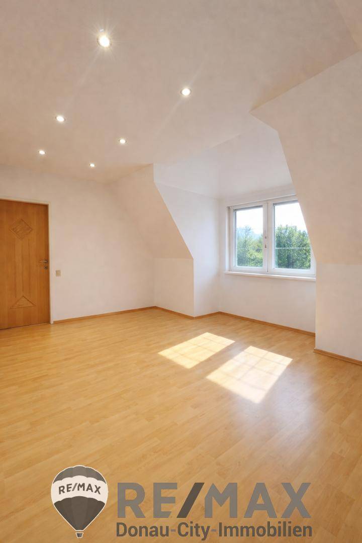 Helles Schlafzimmer im Dachgeschoss mit Dachschrägen und Parkettboden.