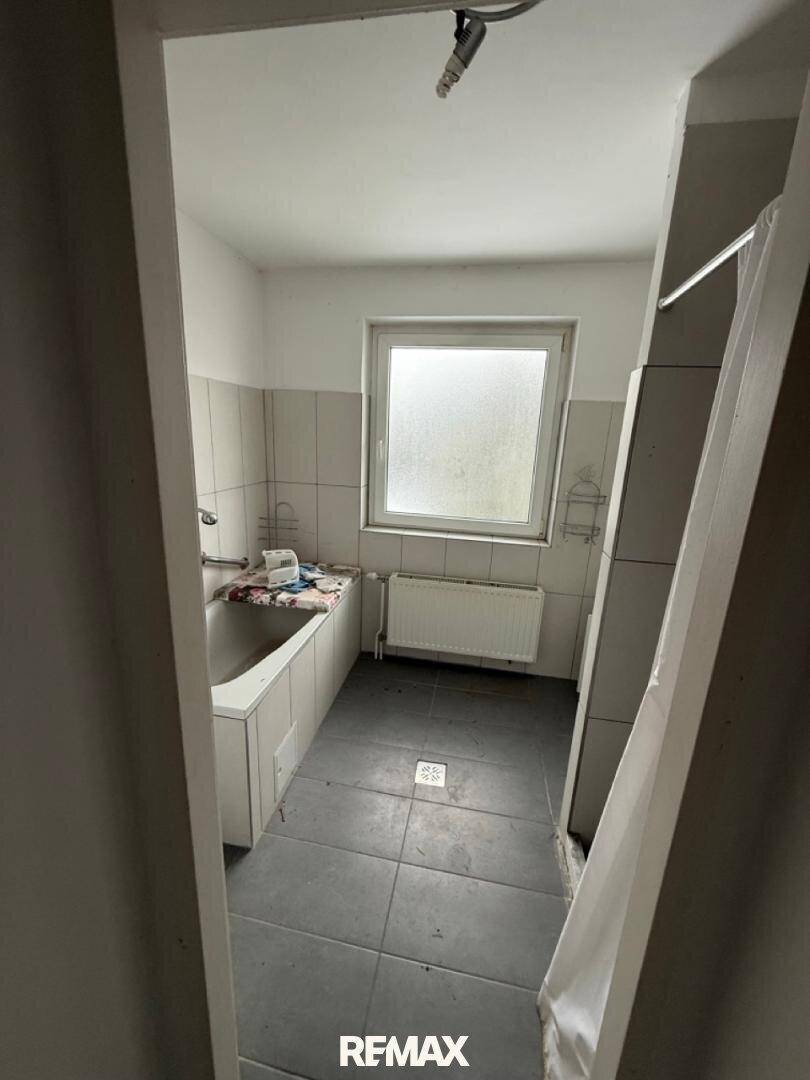 Gefliestes Badezimmer mit Badewanne, Waschbecken und einem Fenster.