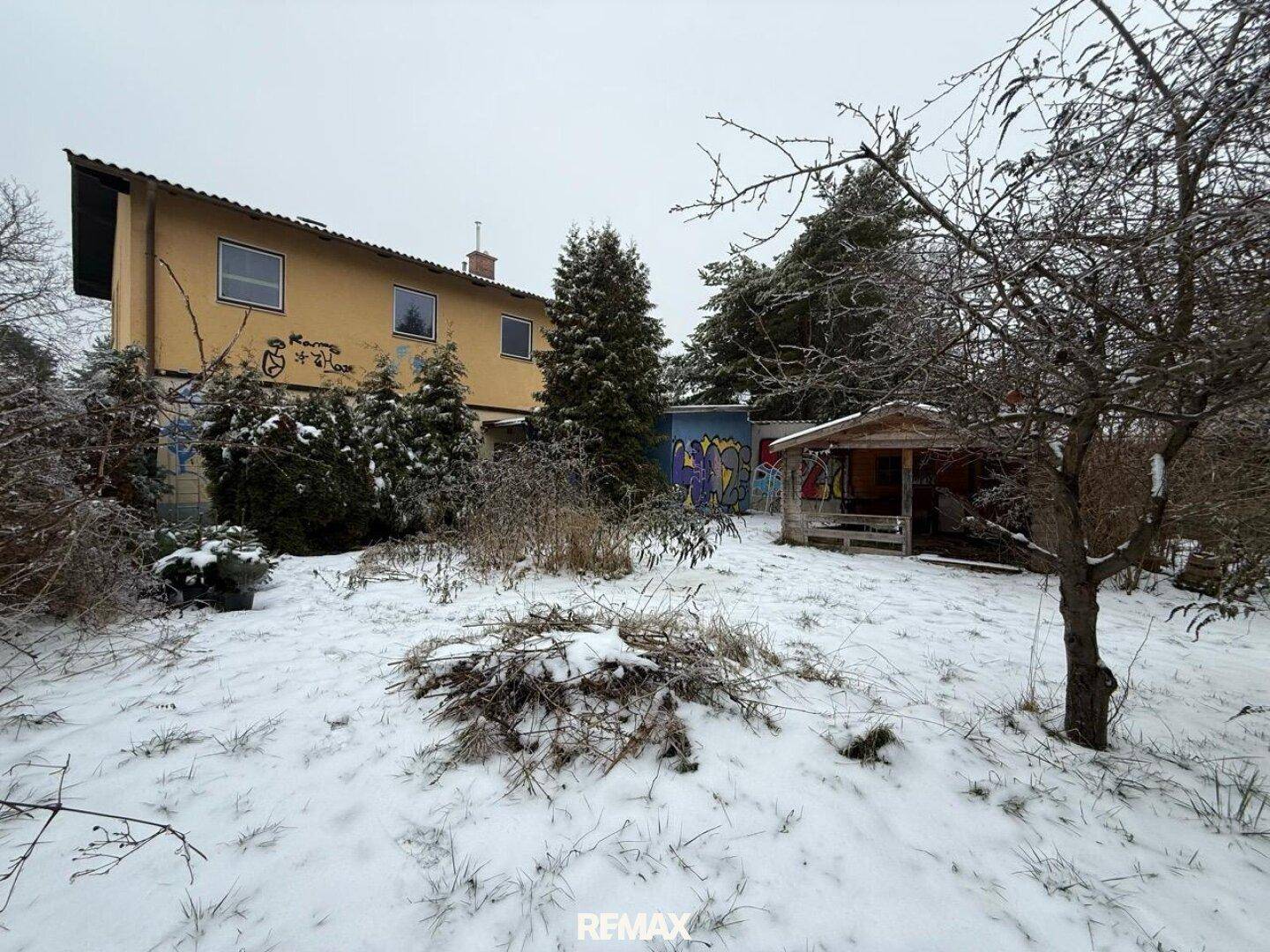 Verschneiter Garten mit Blick auf das Haus und ein Gartenhaus im Winter.