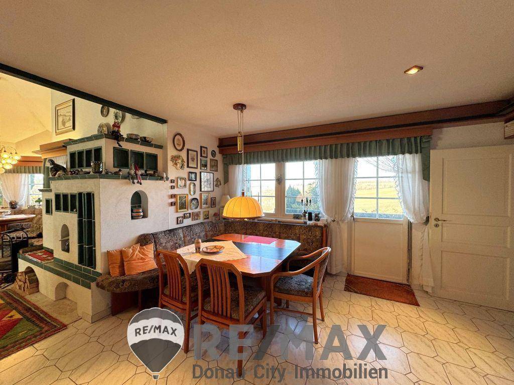 Gemütlicher Essbereich mit Eckbank, Kachelofen und großen Fenstern mit Weitblick.