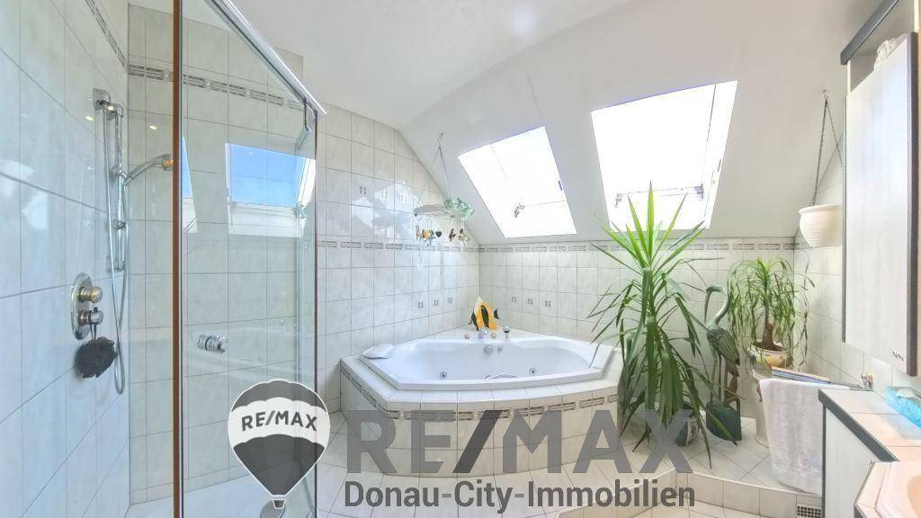 Helles Badezimmer mit Eckwhirlpool, Dusche und Dachfenstern für viel Tageslicht.