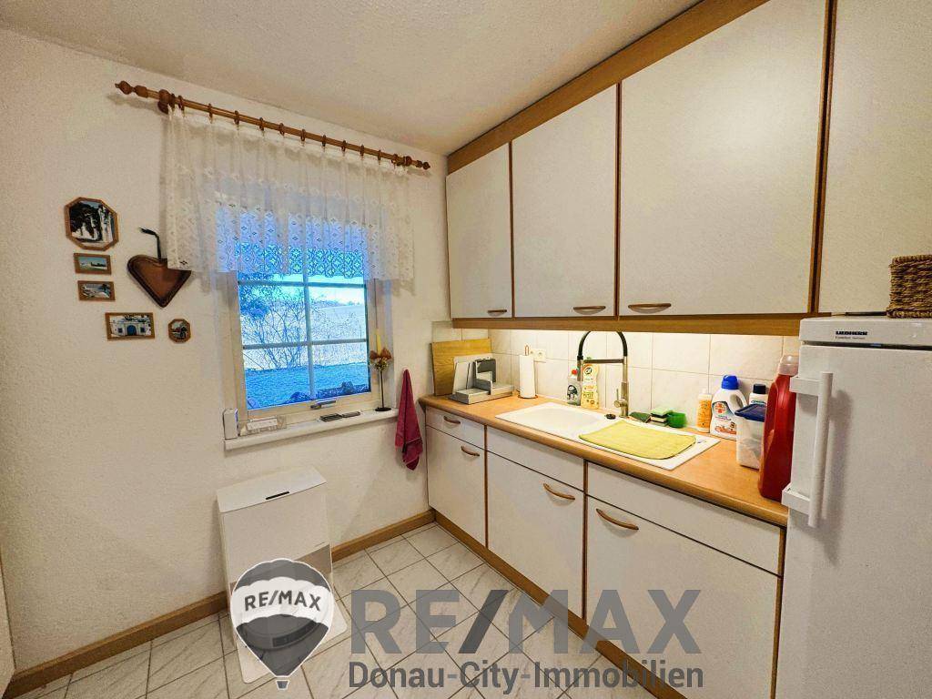 Praktischer Hauswirtschaftsraum mit Spüle, weißen Schränken und Fenster mit Blick ins Grüne.