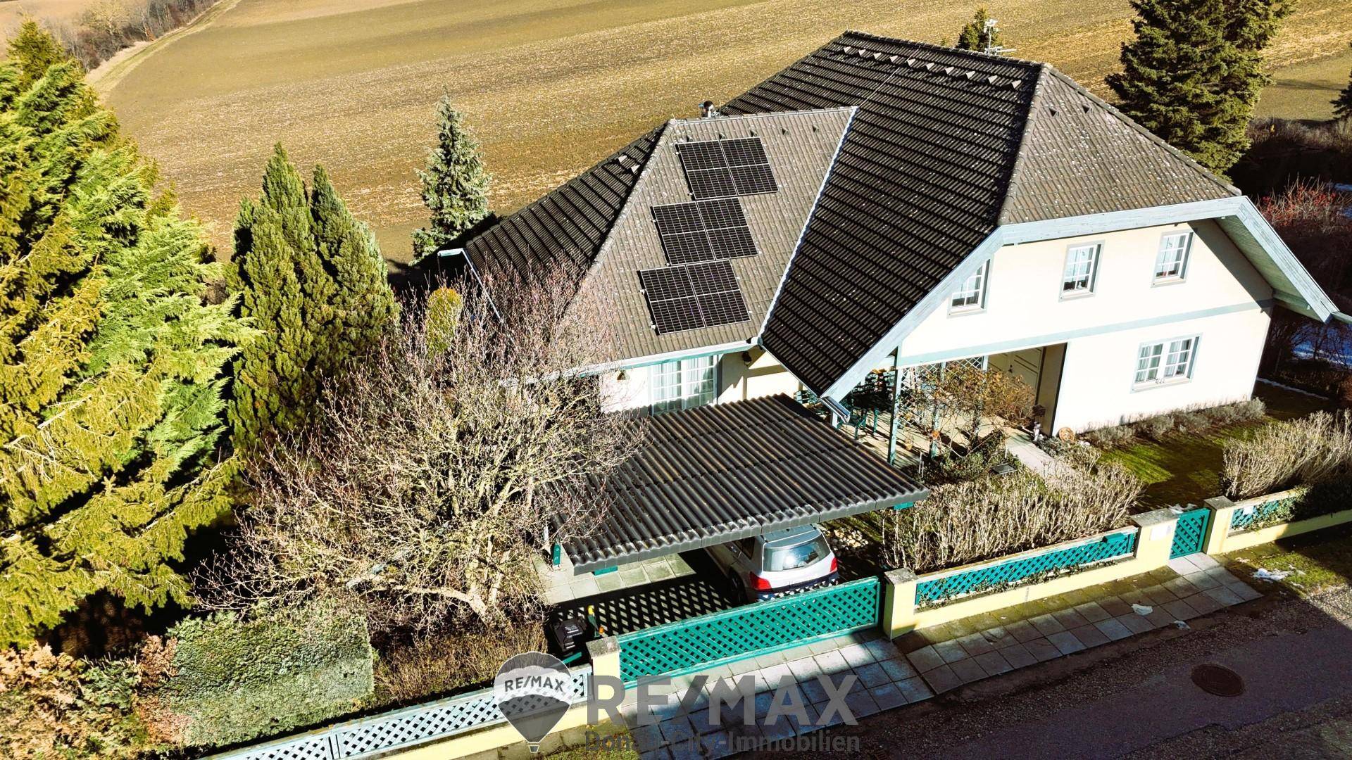 Luftaufnahme des Einfamilienhauses mit Solaranlage, Carport und umliegender Landschaft.