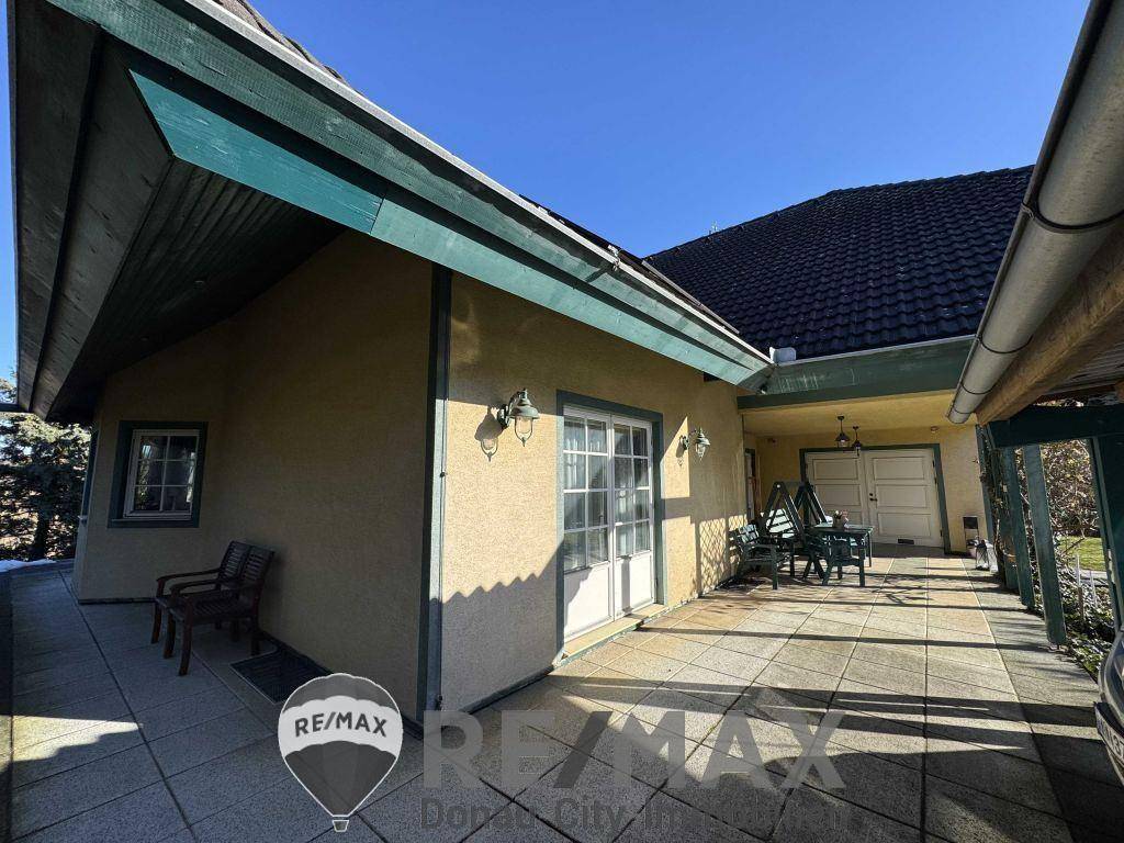 Große gepflasterte Terrasse am Haus mit Sitzgelegenheiten und Zugang zur Garage.