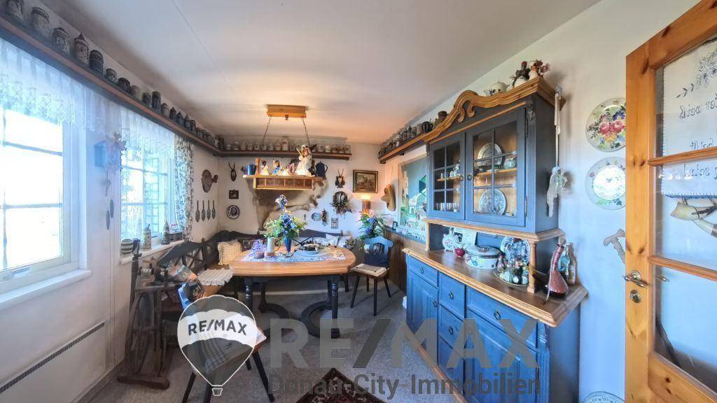 Rustikaler Essbereich mit Holztisch, blauer Anrichte und vielen traditionellen Dekorationen.