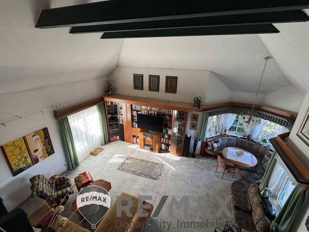 Helles Wohnzimmer mit Teppichboden, großer Fensterfront und integrierten Bücherregalen.