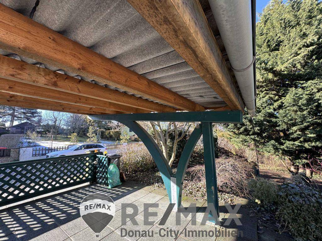 Überdachter Carport mit Holzbalkenkonstruktion und Blick auf die Straße.