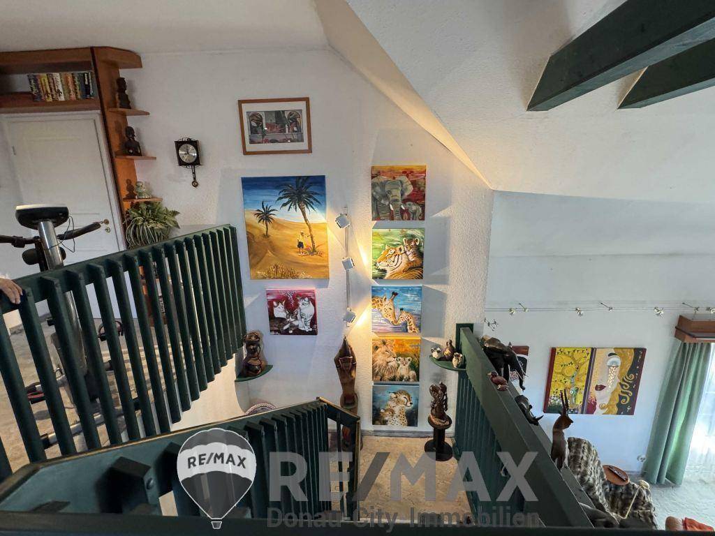 Treppenaufgang zu einer Galerie mit Kunstwerken an der Wand und Blick in den unteren Wohnbereich.