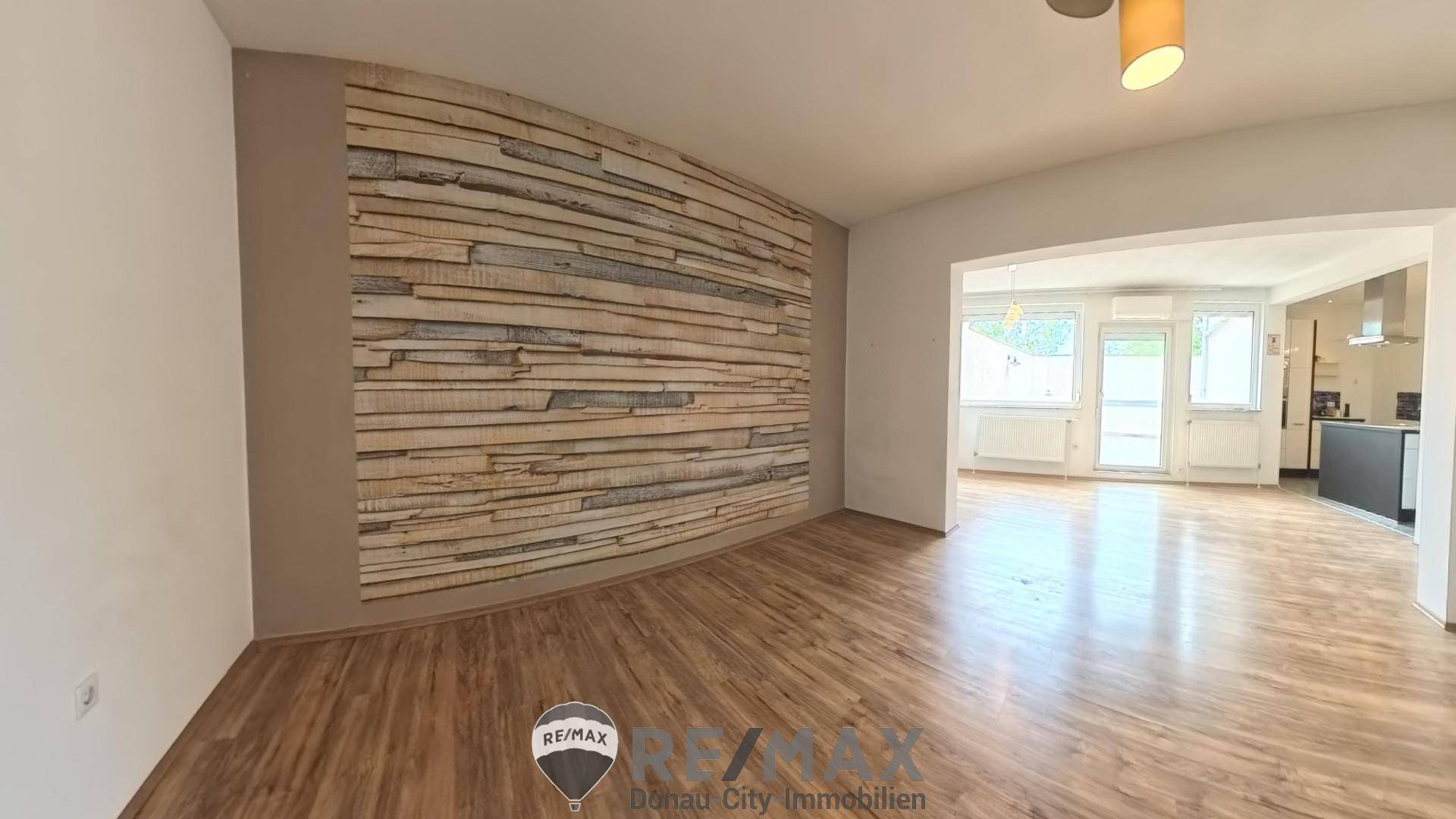 Heller Wohnbereich mit Holzwandverkleidung und Zugang zu einem weiteren Raum.