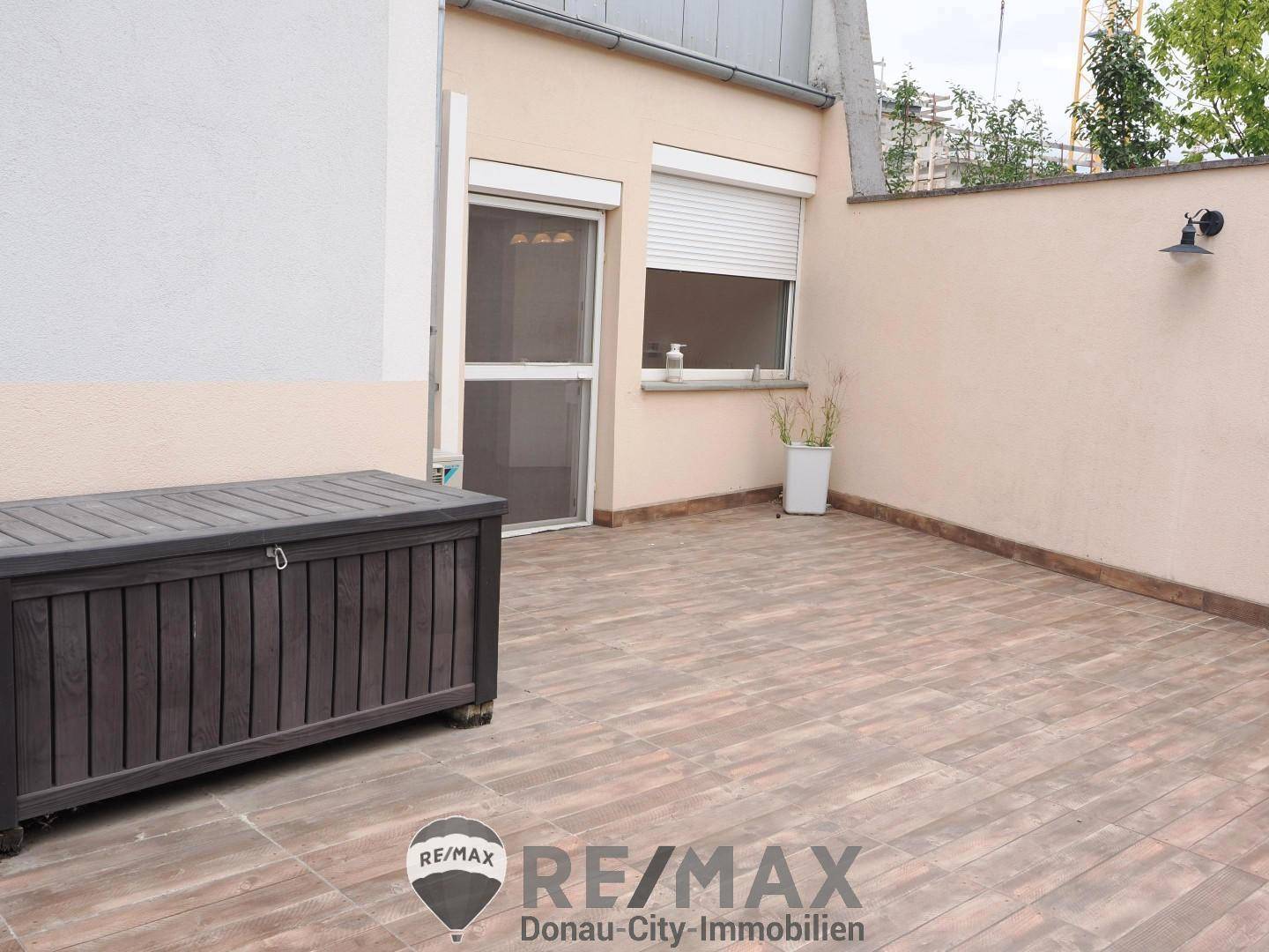 Geräumige, geflieste Terrasse mit Sichtschutz und Stauraumkiste für entspannte Stunden im Freien.
