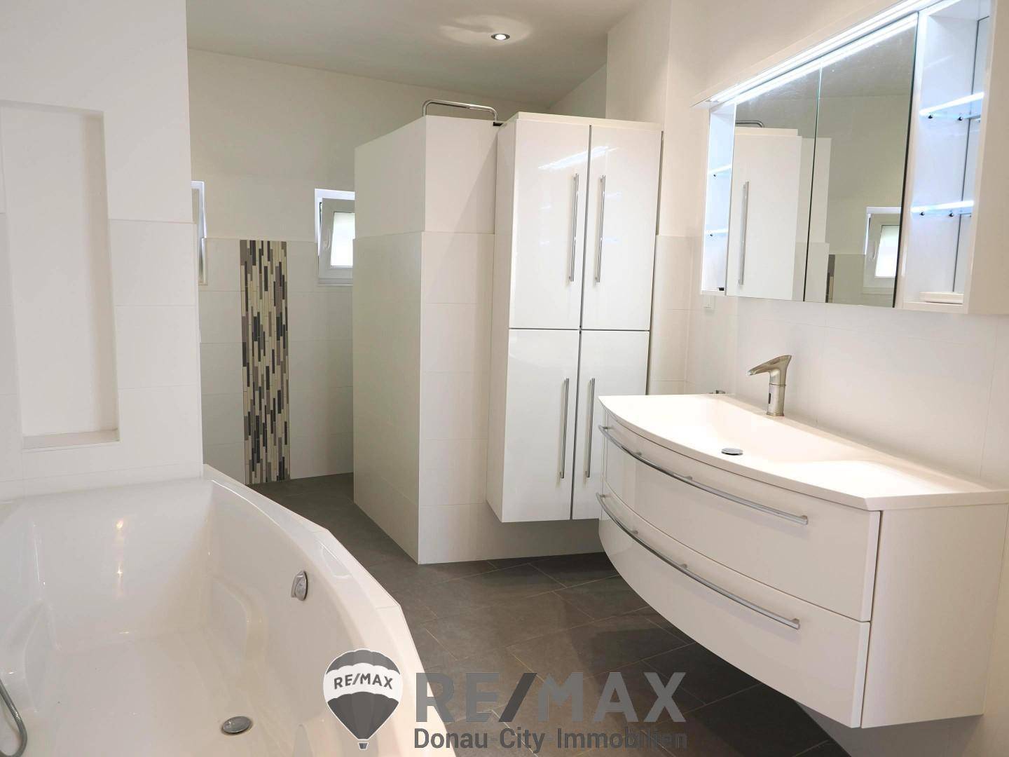 Modernes Badezimmer mit Badewanne, schwebendem Waschtisch und Spiegelschrank.