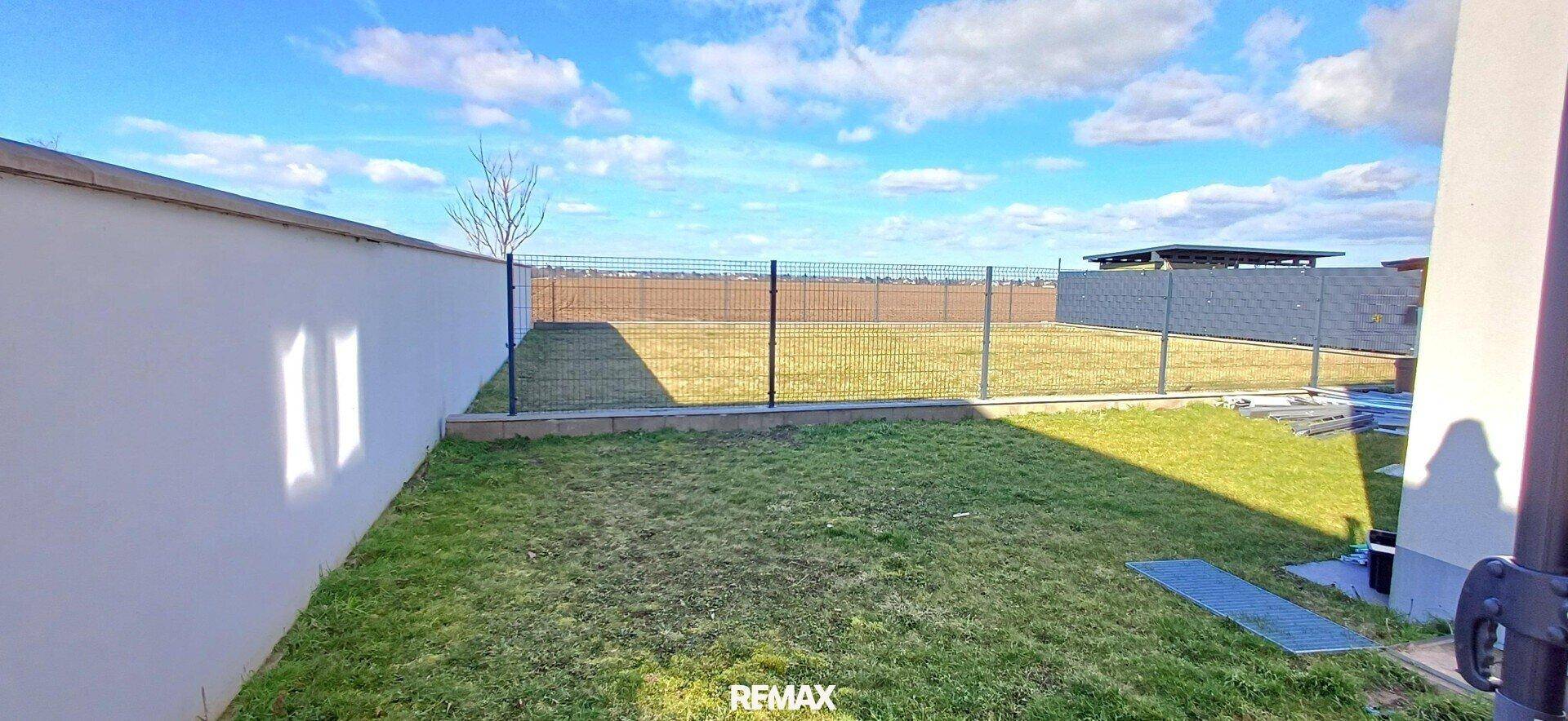 Gepflegter Gartenbereich mit Rasenfläche und Zaun, ideal für Entspannung im Freien.