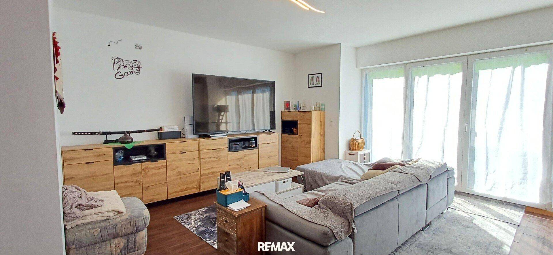 Gemütliches Wohnzimmer mit großem Sofa, TV-Möbeln und viel Tageslicht durch die Terrassentür.