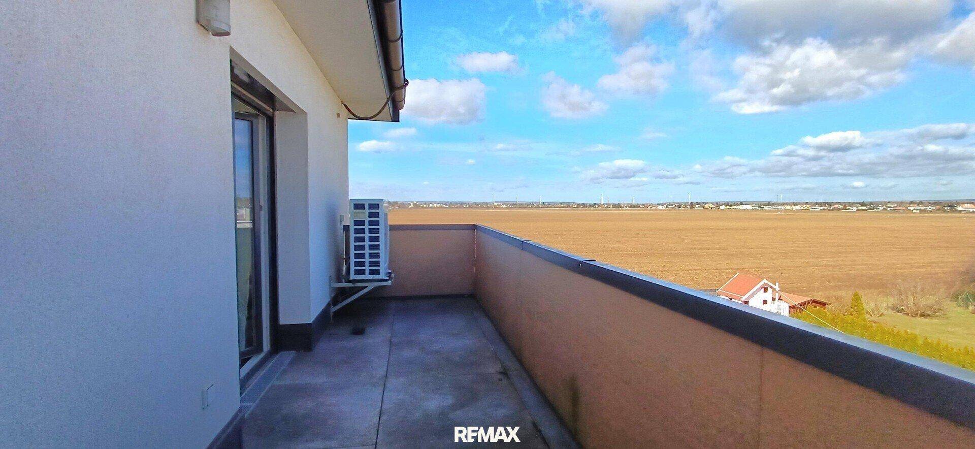 Geräumiger Balkon mit weitem Blick über die umliegende Landschaft und Felder.