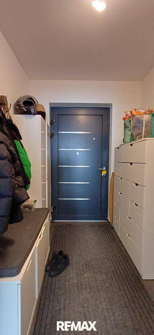 Eingangsbereich mit dunkler Eingangstür, Garderobe und praktischen Kommoden.