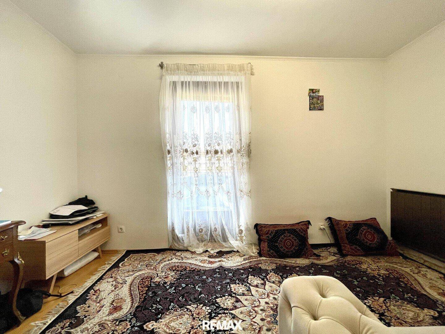Helles Schlafzimmer mit Fenster, Teppichboden und einfacher Einrichtung.