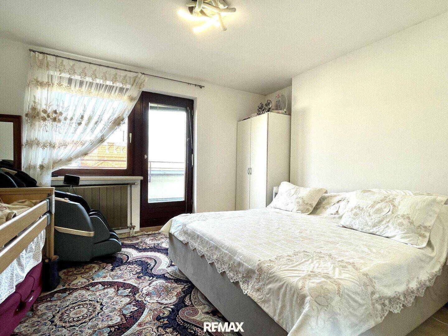 Gemütliches Schlafzimmer mit Doppelbett, Teppichboden und Zugang zum Balkon.