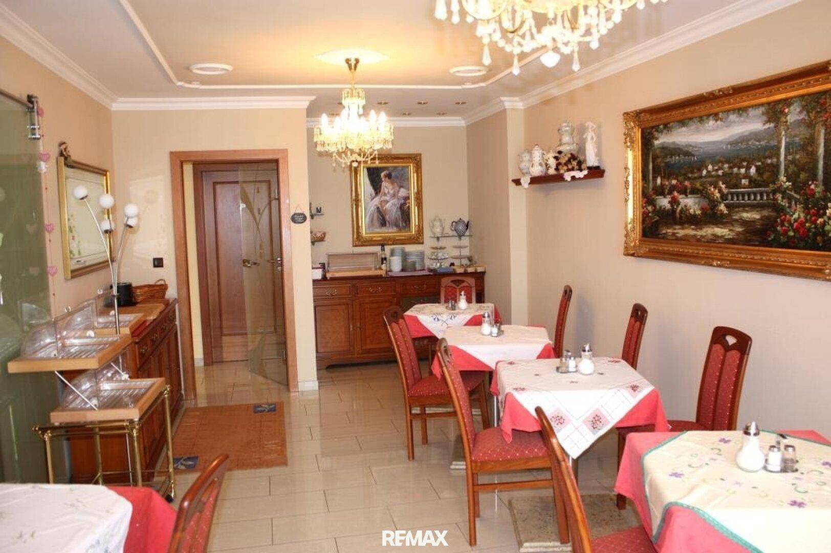 Gemütlicher Speisesaal mit mehreren Tischen, roten Stühlen und traditioneller Dekoration.
