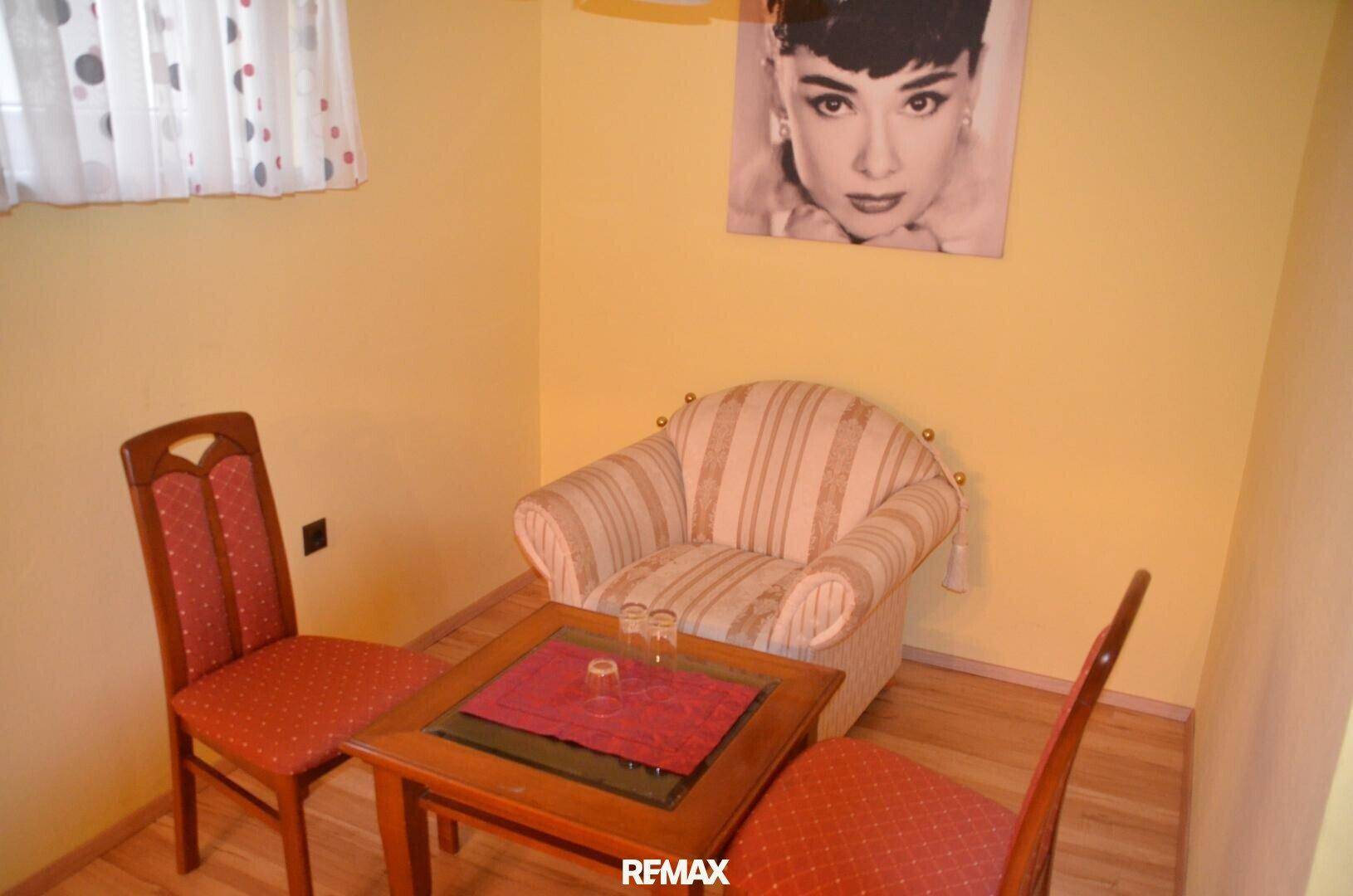 Kleine Sitzecke mit gelben Wänden, Holzboden und einem Bild von Audrey Hepburn.
