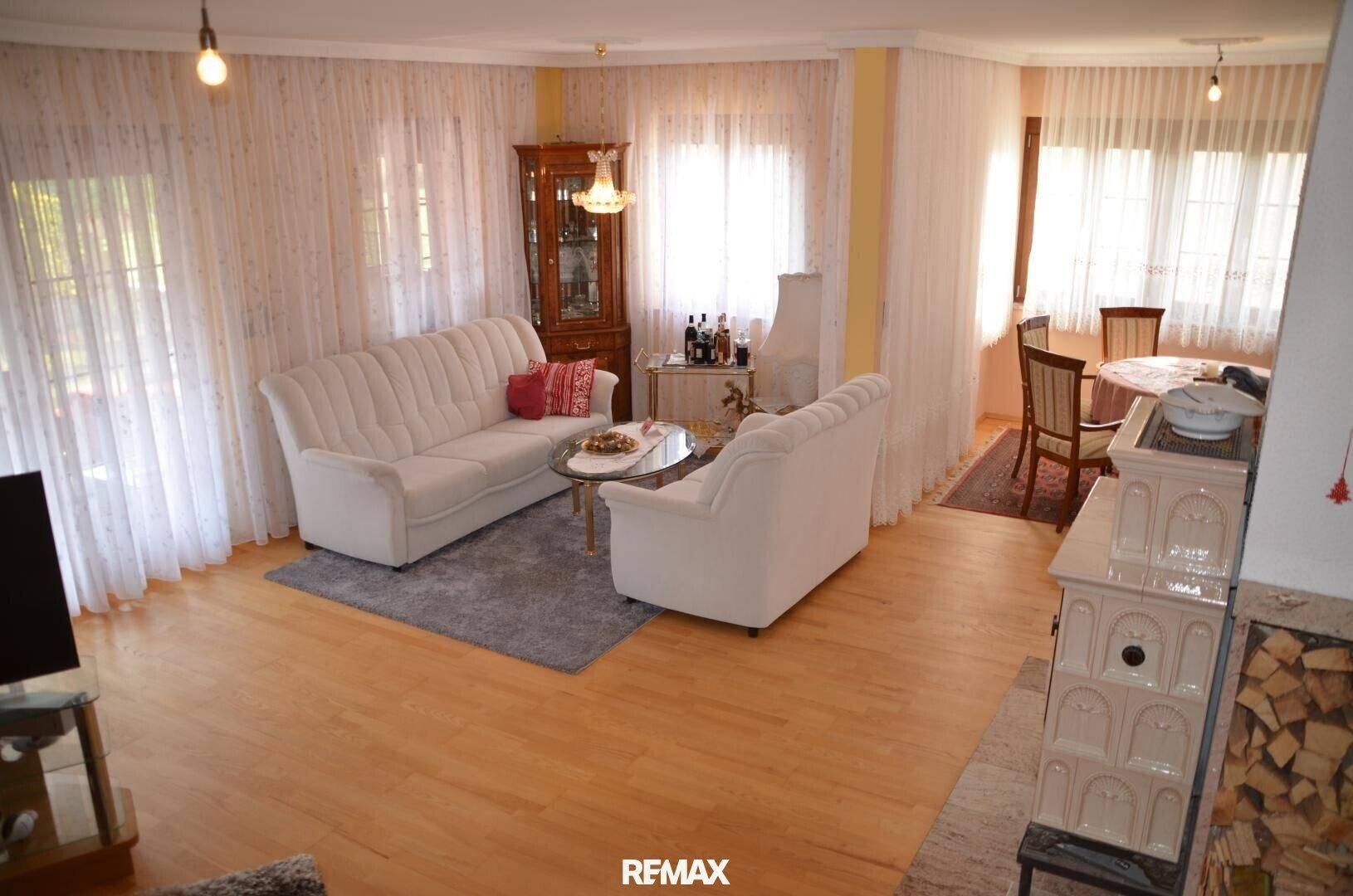 Geräumiger Wohn- und Essbereich mit hellem Holzboden, bequemen Sofas und Kaminofen.