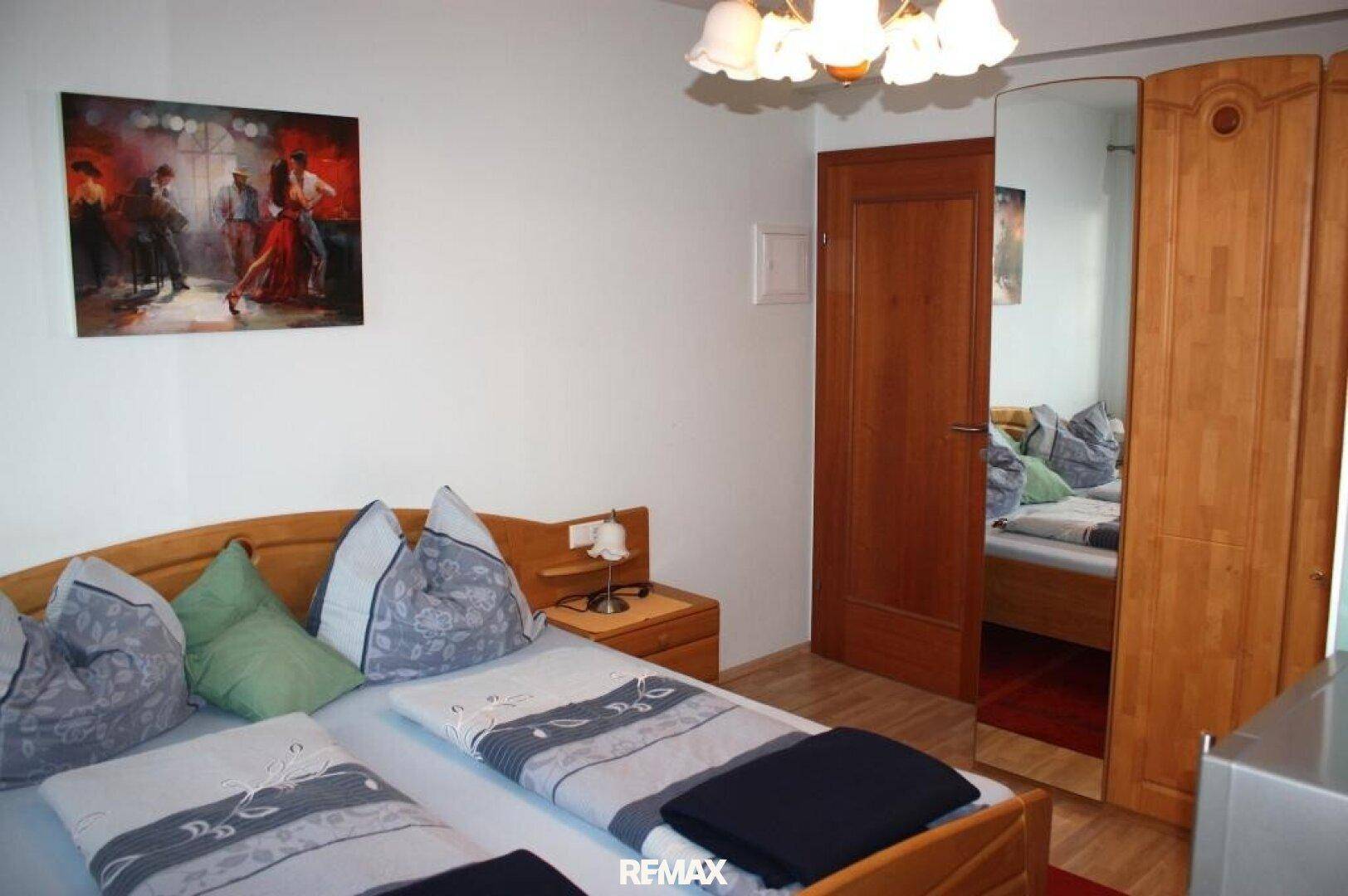 Schlafzimmer mit Doppelbett, Holzmöbeln und einem praktischen Spiegelkleiderschrank.
