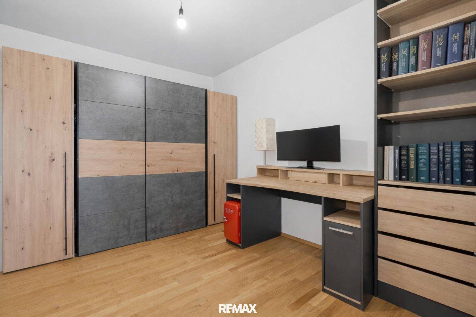 Geräumiges Zimmer mit modernem Kleiderschrank, Schreibtisch und Bücherregal für viel Stauraum.
