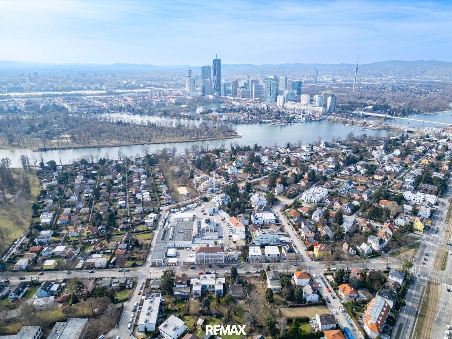 Panoramablick aus der Vogelperspektive auf die Stadt mit Fluss und Skyline im Hintergrund.