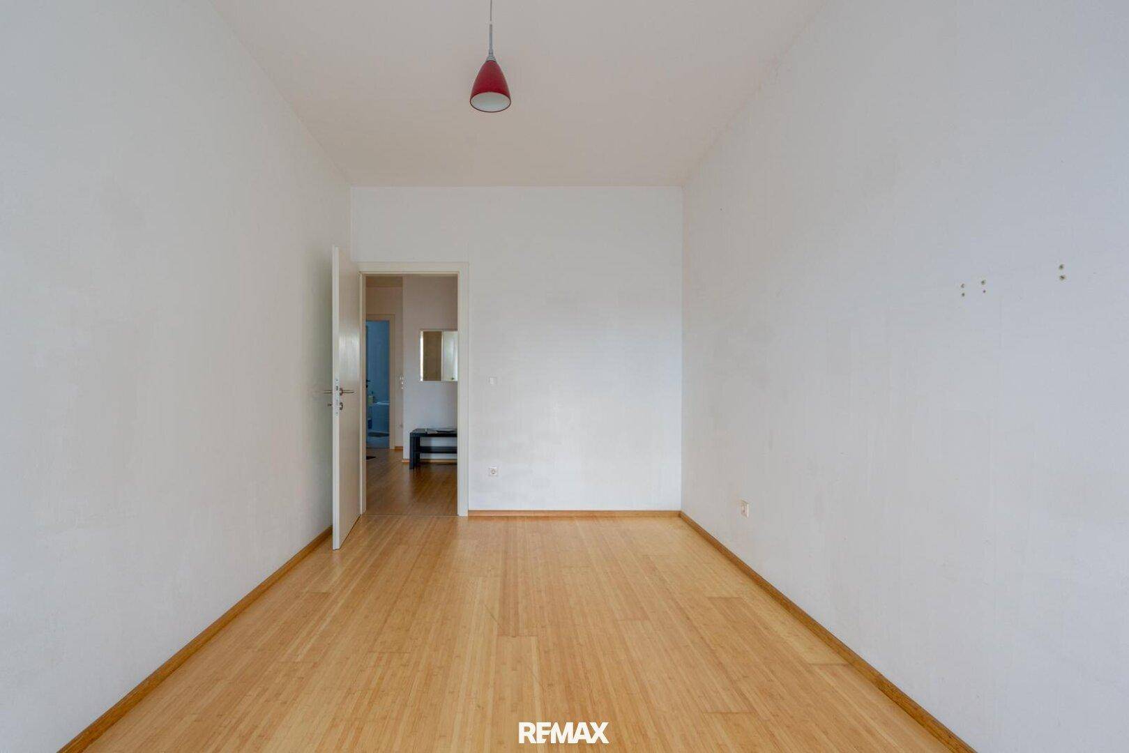 Leeres Zimmer mit hellem Holzfußboden und weiß gestrichenen Wänden, bereit zur Einrichtung.