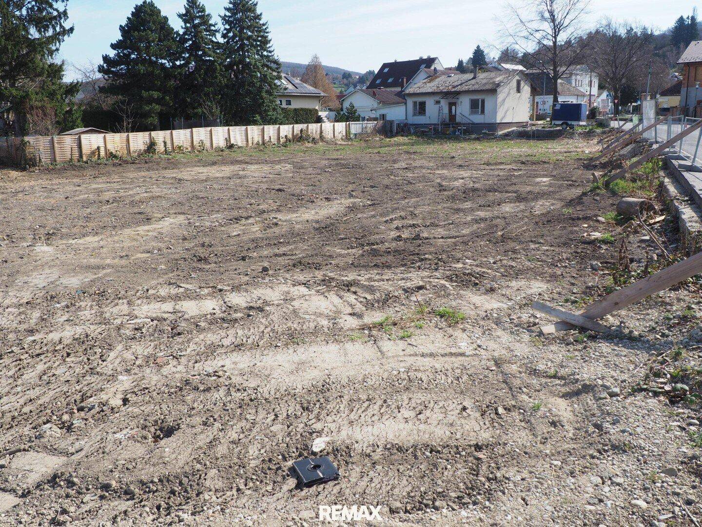 Weitläufiges unbebautes Grundstück mit Spuren von Fahrzeugen und angrenzender Straße.