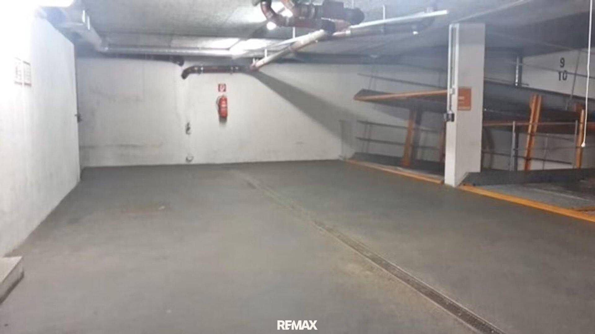 Geräumige Tiefgarage mit Betonwänden und -boden sowie sichtbaren Leitungen an der Decke.