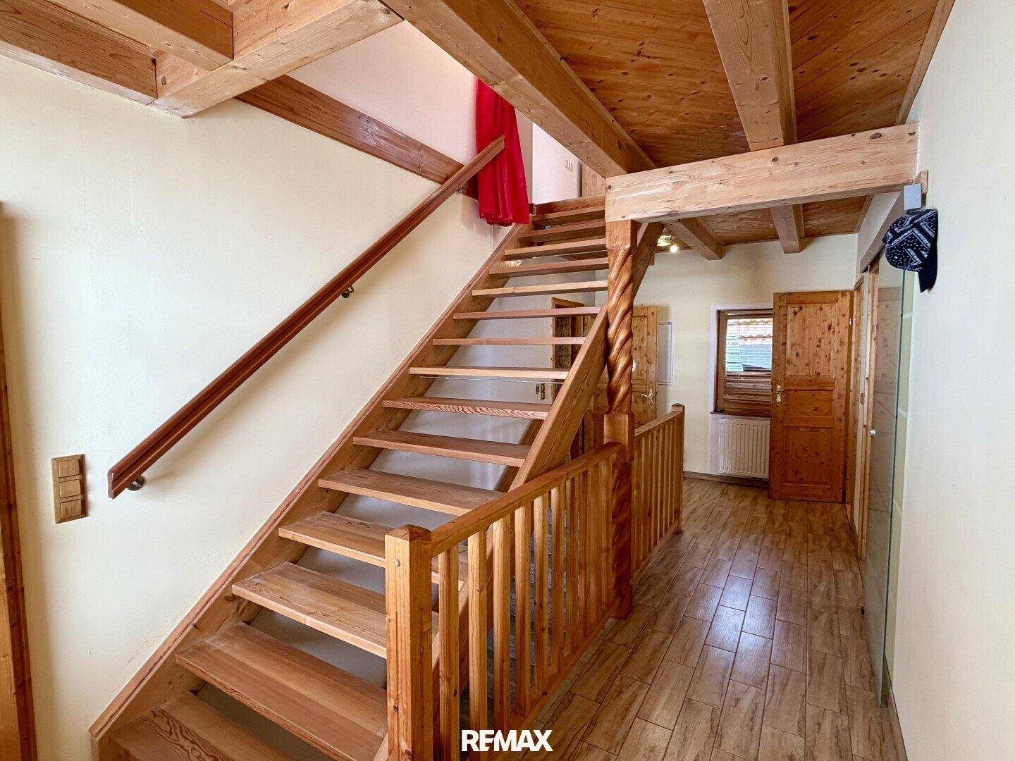 Helles Treppenhaus mit Holztreppe und Geländer, das zu den oberen Etagen führt.