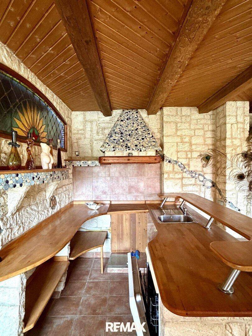 Rustikale Küchenzeile mit Holztheke, Spüle und dekorativem Mosaik an der Wand.