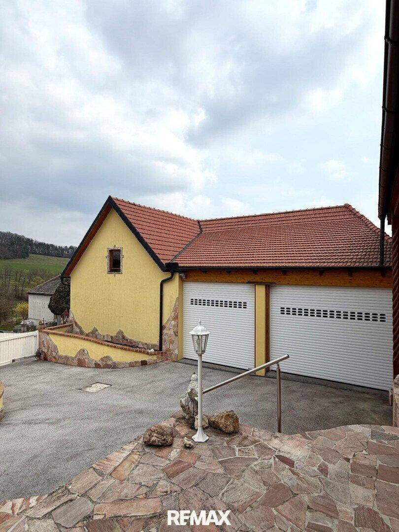 Doppelgarage mit Rolltoren und gepflasterter Zufahrt neben dem Wohnhaus.