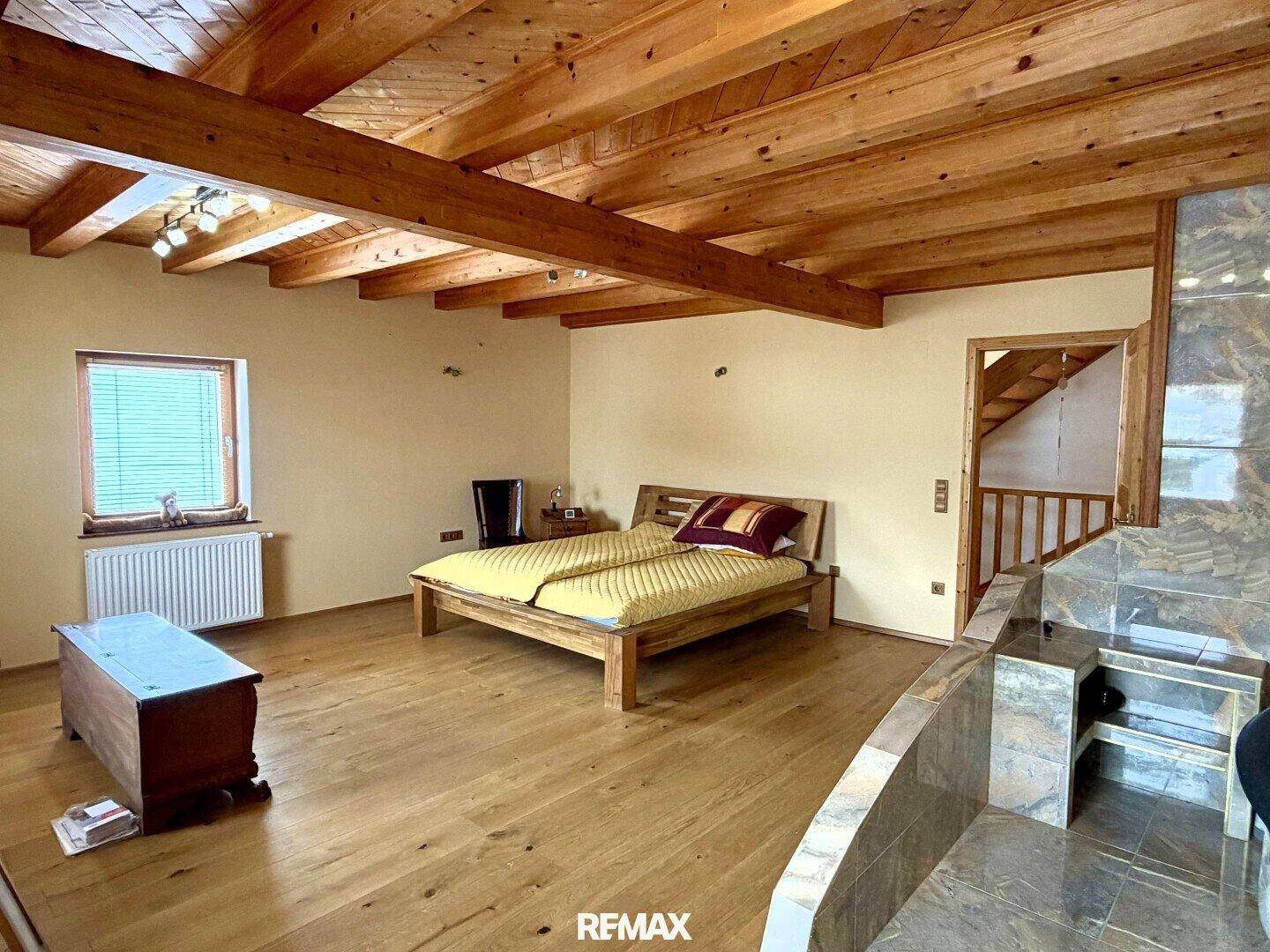 Gemütliches Schlafzimmer mit Holzbalkendecke, Doppelbett und Zugang zu einem Treppenhaus.