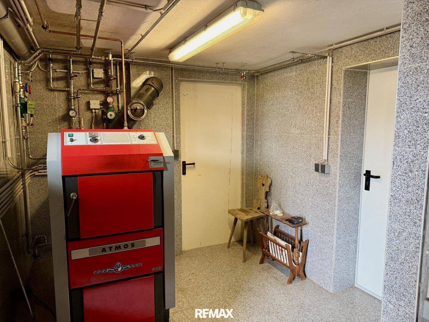 Heizungsraum mit einem modernen Holzvergaserofen und sichtbaren Rohrleitungen.