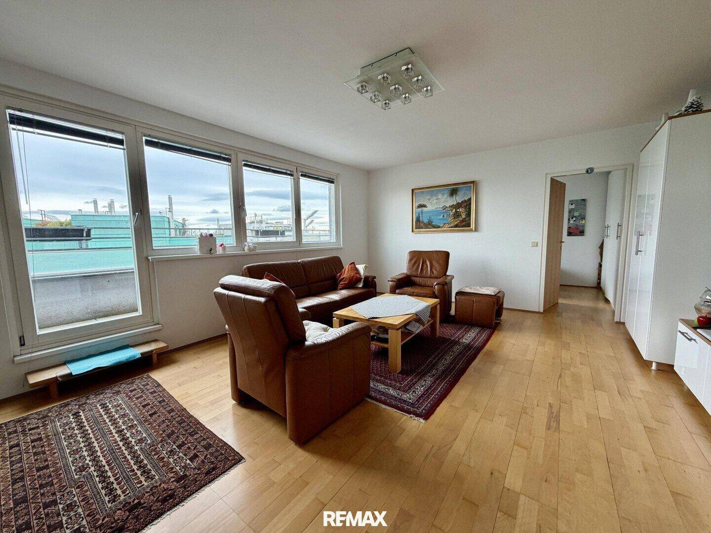 Gemütliches Wohnzimmer mit Ledersofas, Teppich und Zugang zu einem möglichen Balkon.