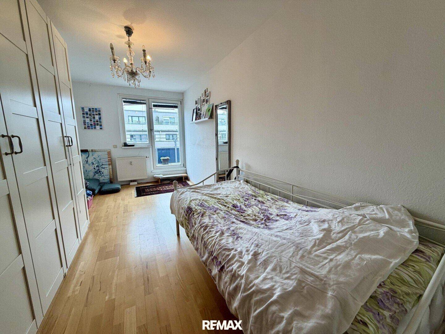 Schlafzimmer mit Holzboden, Kronleuchter und einem Einzelbett, das viel Platz bietet.