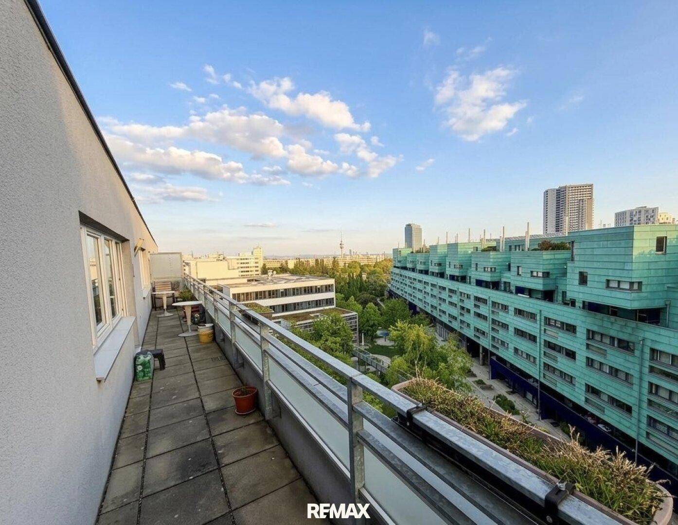 Langer Balkon mit Stadtblick und viel Grün, ideal für entspannte Stunden im Freien.