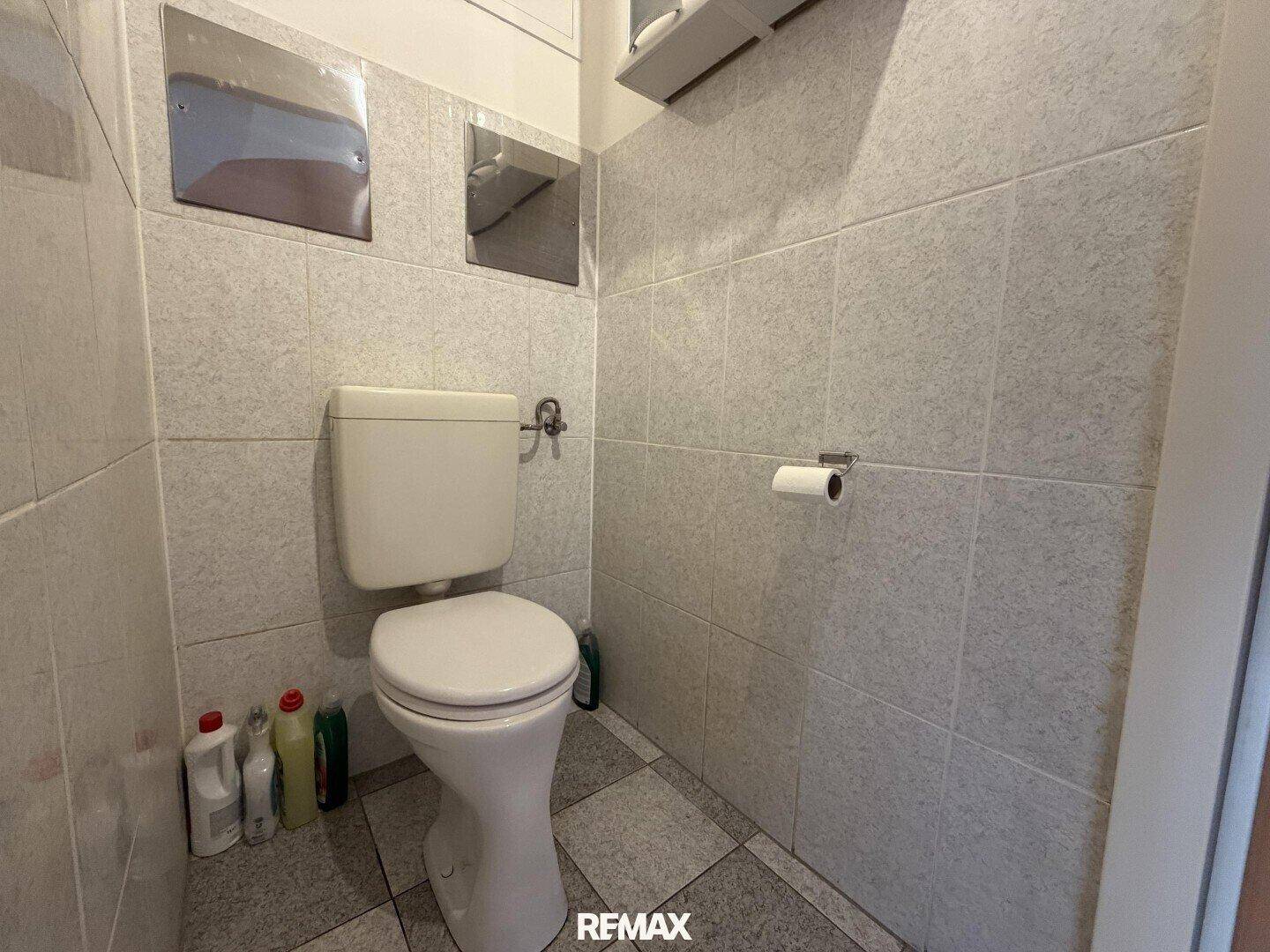 Separate Toilette mit Fliesen an Wänden und Boden, einfach und funktional.