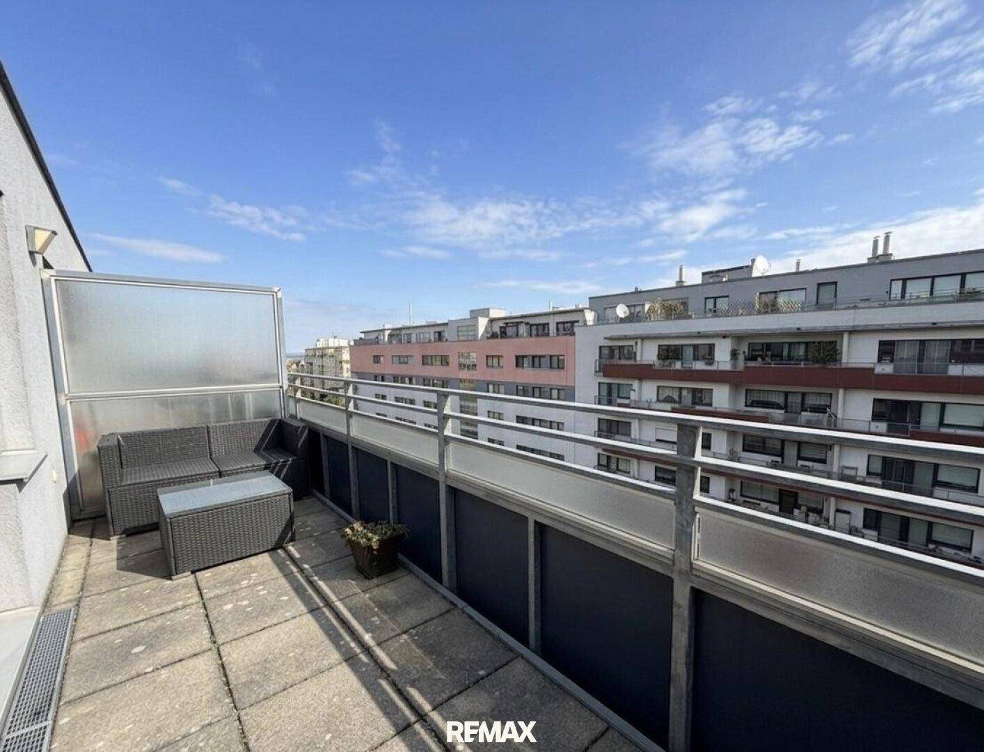 Geräumiger Balkon mit Lounge-Möbeln und weitem Blick über die umliegenden Gebäude.