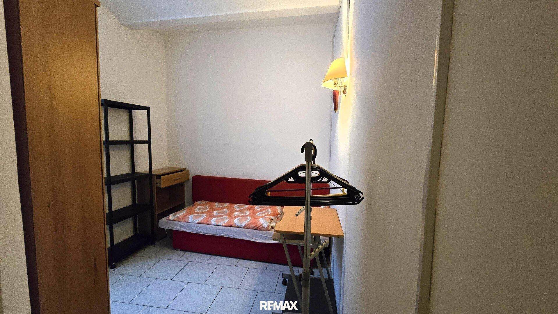 Kleines Schlafzimmer mit Einzelbett, einem Regal und einem Kleiderschrank aus Holz.