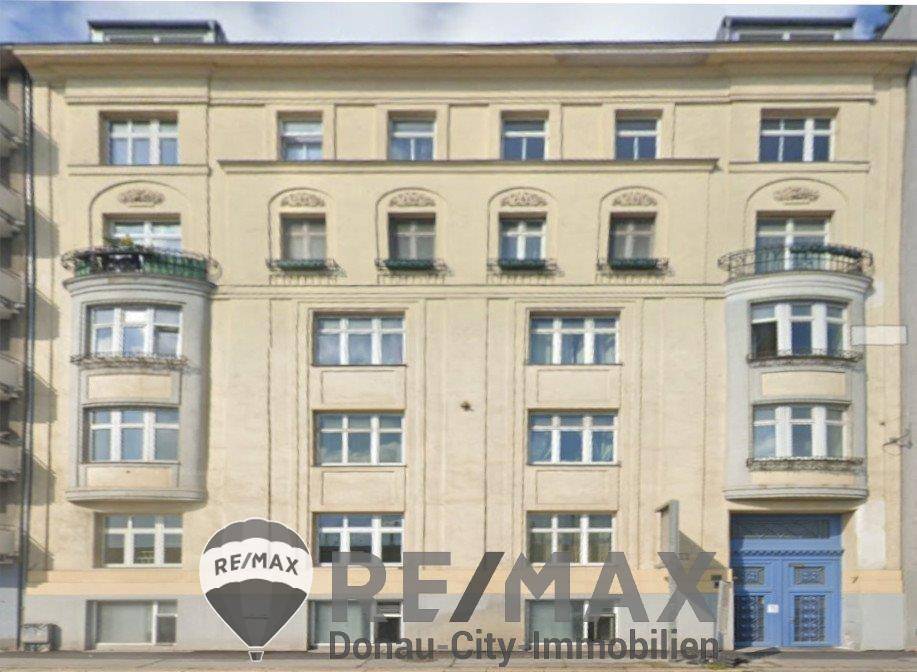 Klassische Fassade eines Mehrfamilienhauses mit zahlreichen Fenstern und dekorativen Balkonen in hellem Beige.