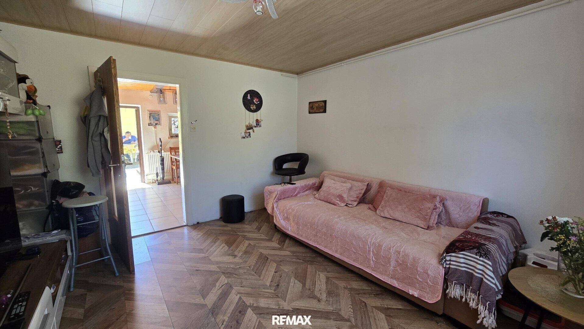 Gemütliches Wohnzimmer mit Sofa und offenem Zugang zu einem weiteren Raum.