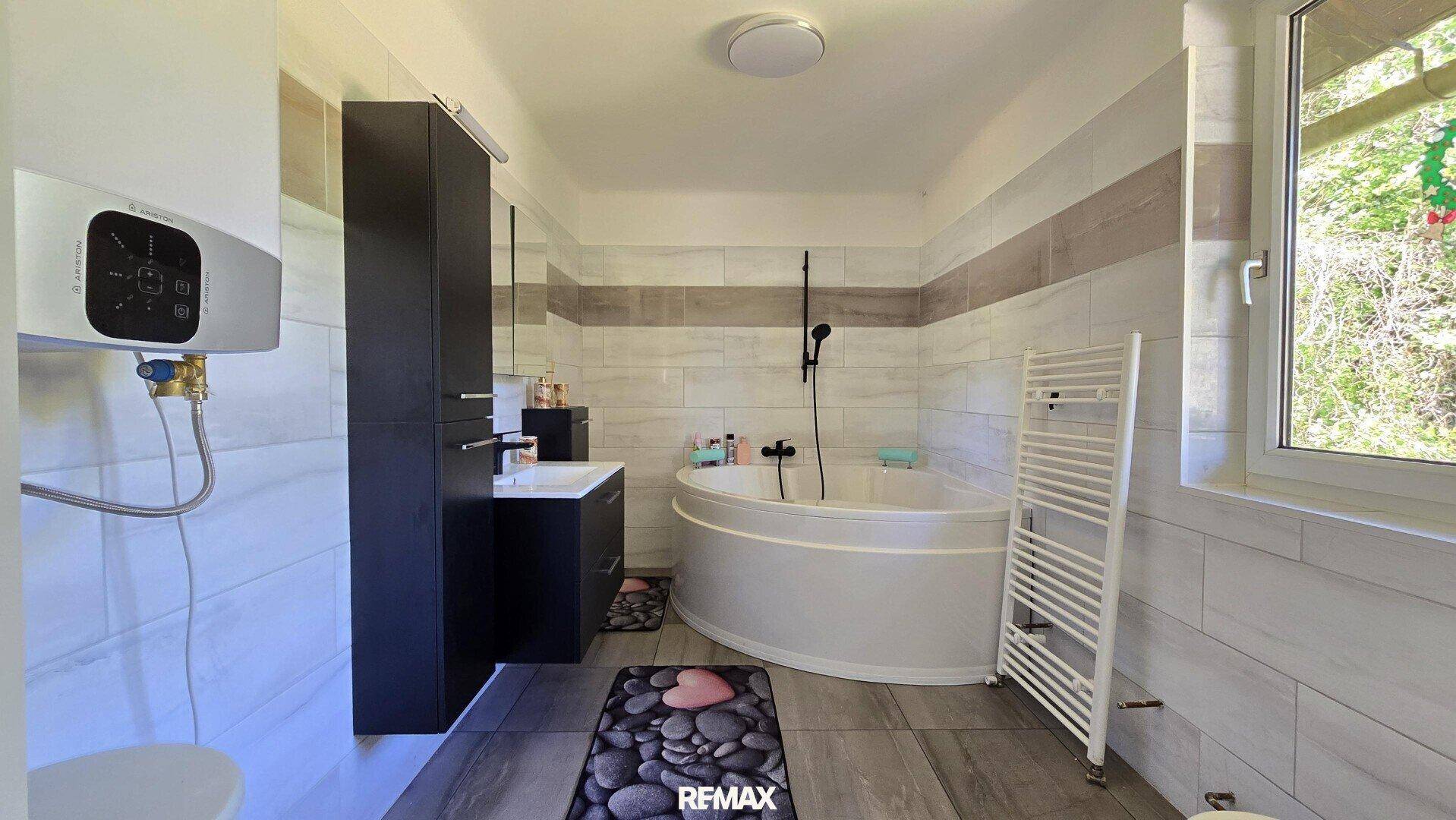 Modernes Badezimmer mit Eckbadewanne, Waschtisch und beheiztem Handtuchhalter.