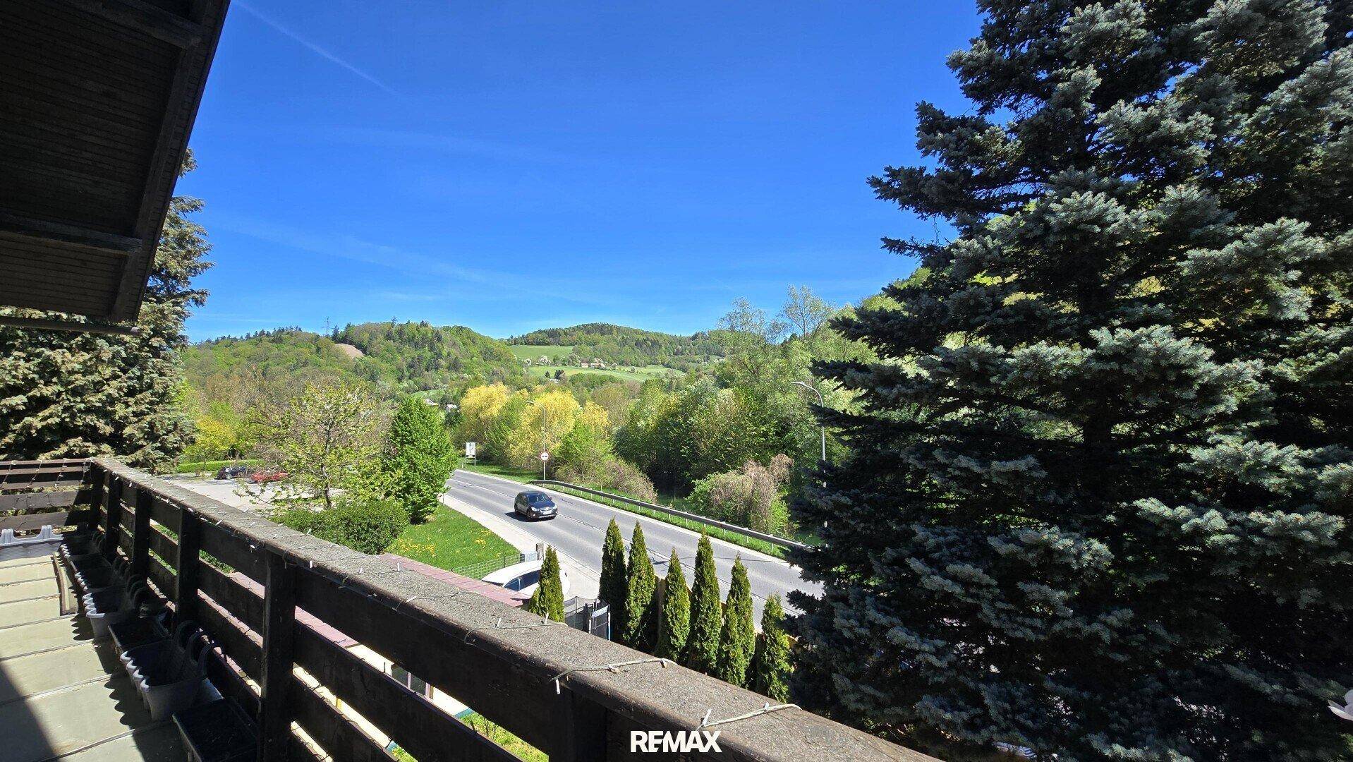 Balkon mit Holzbalkonbrüstung und weitem Blick auf die Landschaft und Straße.