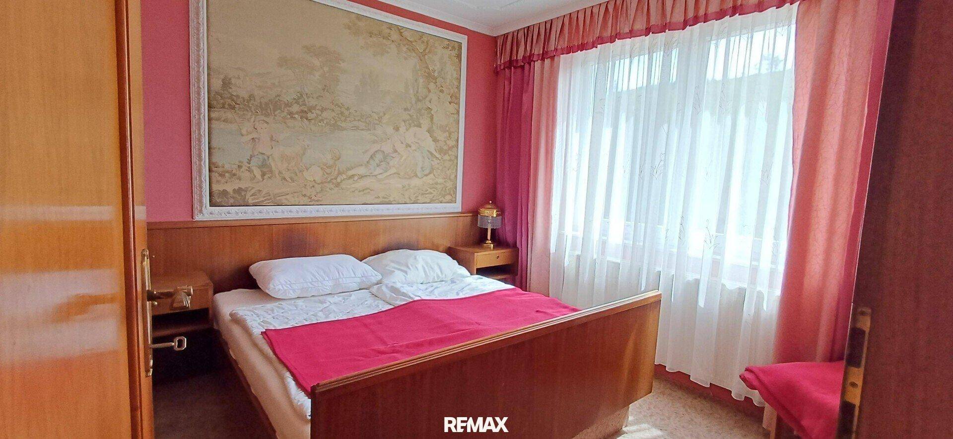 Gemütliches Schlafzimmer mit Doppelbett, Holzmöbeln und einem großen Wandteppich.