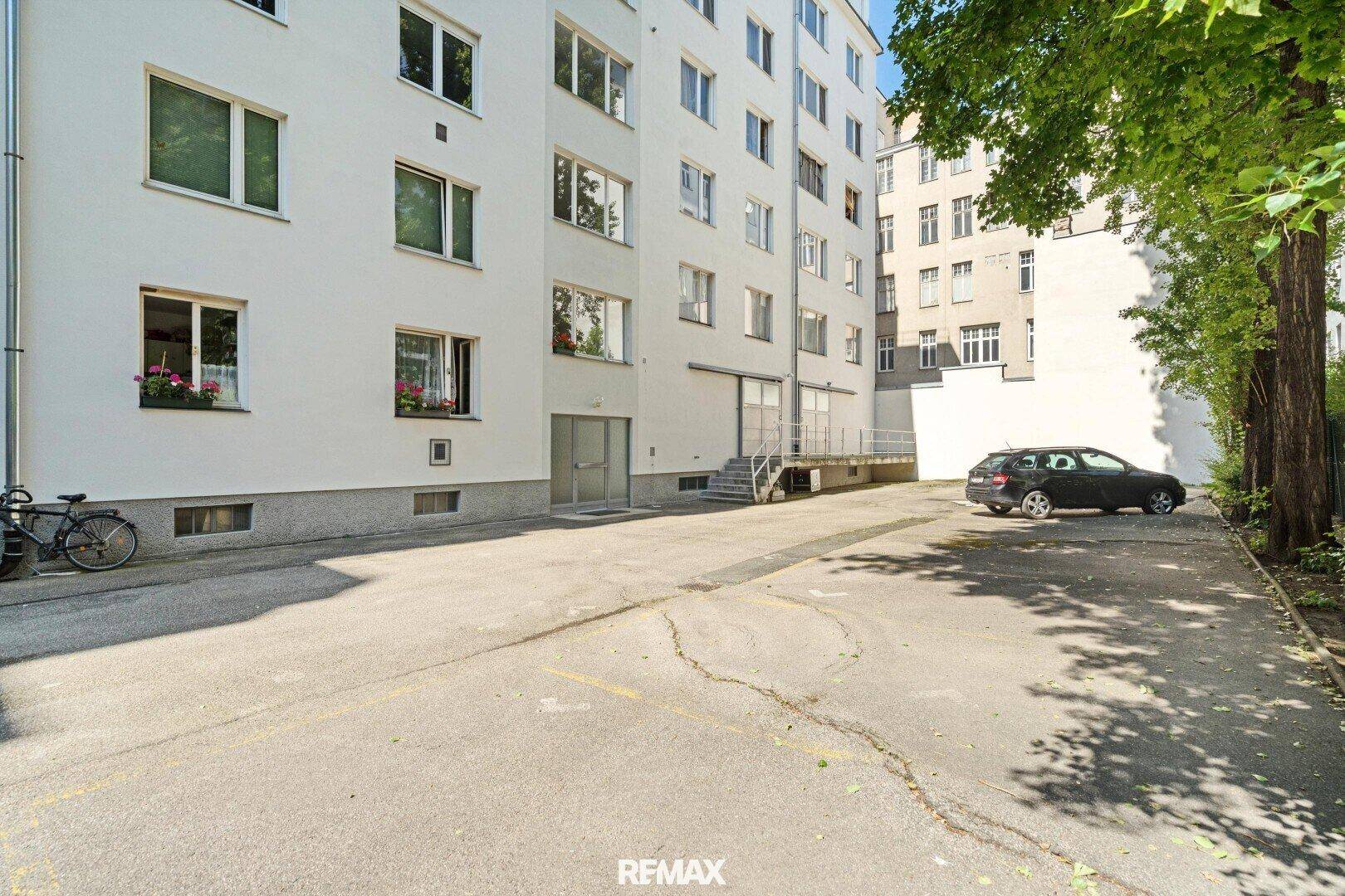 Außenansicht eines Gebäudes mit einem Parkplatz im Freien und Bäumen.